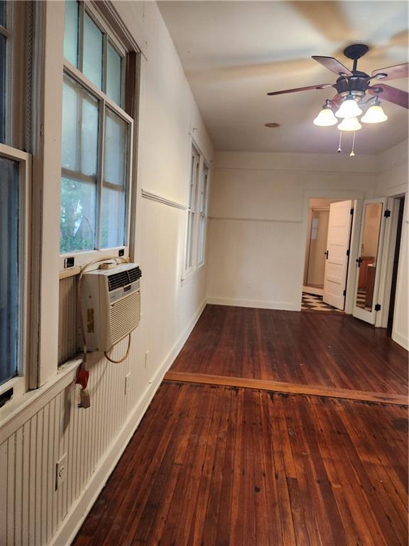 empty room featuring baseboards, ceiling fan, cooling unit, and hardwood / wood-style floors