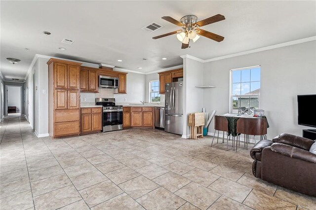 kitchen featuring appliances with stainless steel finishes, ornamental molding, light tile flooring, and ceiling fan