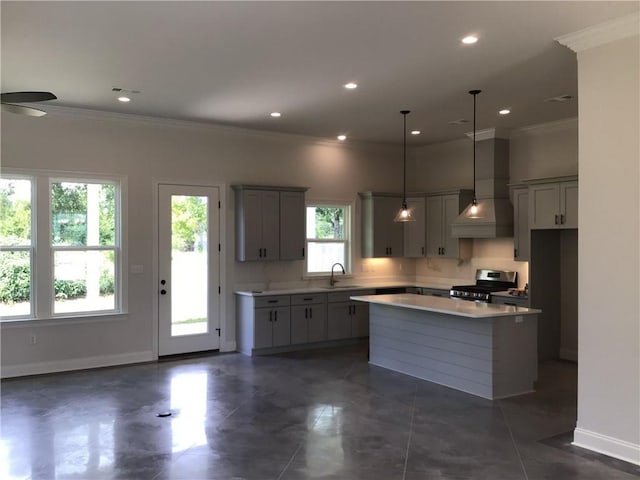 kitchen with stainless steel gas stove, a kitchen island, custom range hood, and plenty of natural light