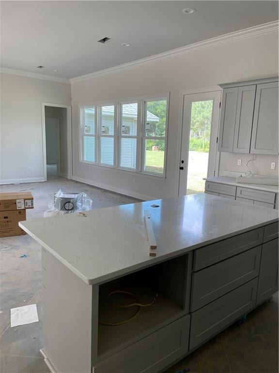 kitchen with gray cabinets, ornamental molding, tile patterned floors, light stone counters, and a center island