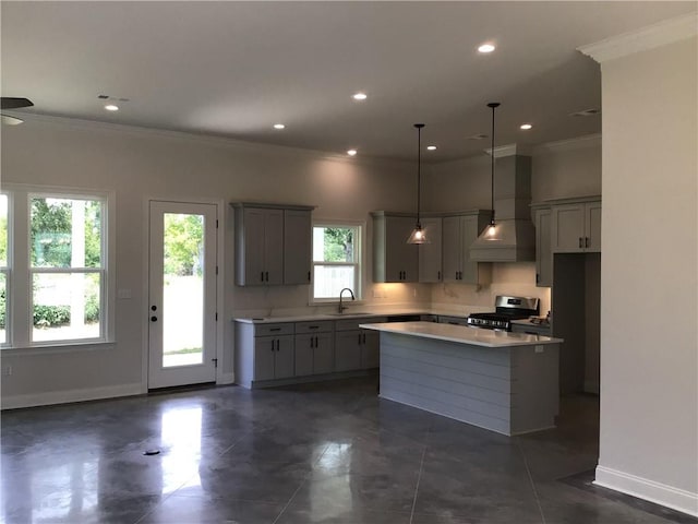 kitchen featuring stainless steel gas stove, decorative light fixtures, custom exhaust hood, a center island, and gray cabinets