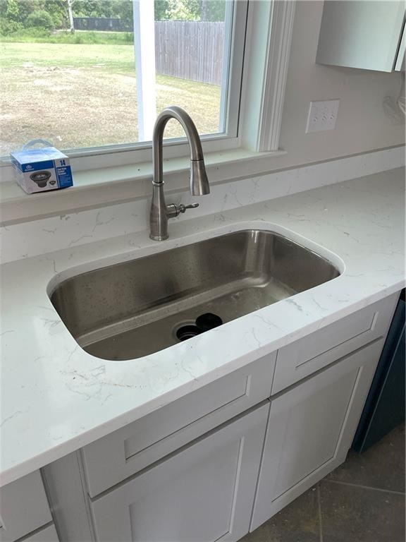 interior details featuring sink, light stone counters, and dark tile patterned flooring