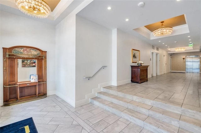 hallway featuring a raised ceiling and a notable chandelier