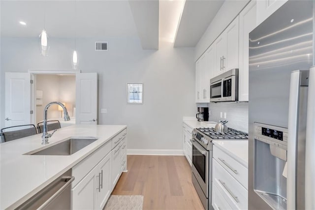 kitchen featuring pendant lighting, white cabinetry, sink, and stainless steel appliances