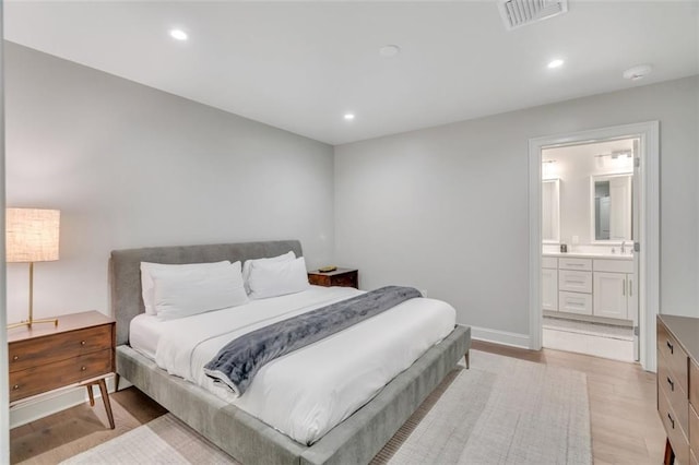 bedroom featuring ensuite bathroom, sink, and light hardwood / wood-style flooring