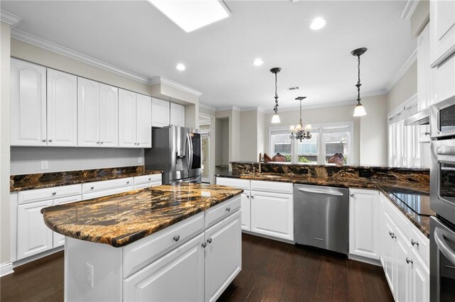 kitchen with hanging light fixtures, dark hardwood / wood-style floors, stainless steel appliances, and a kitchen island