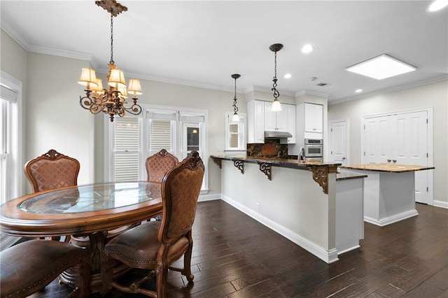 dining room with sink, dark hardwood / wood-style flooring, crown molding, and a chandelier