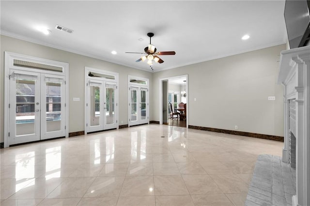 unfurnished living room with a brick fireplace, light tile flooring, ceiling fan, ornamental molding, and french doors