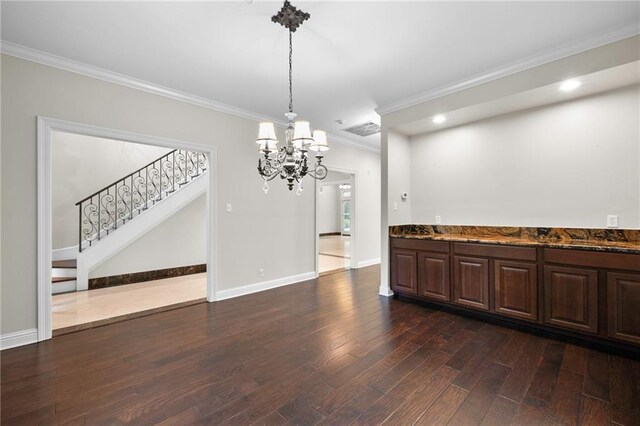 unfurnished dining area featuring ornamental molding, dark wood-type flooring, and an inviting chandelier