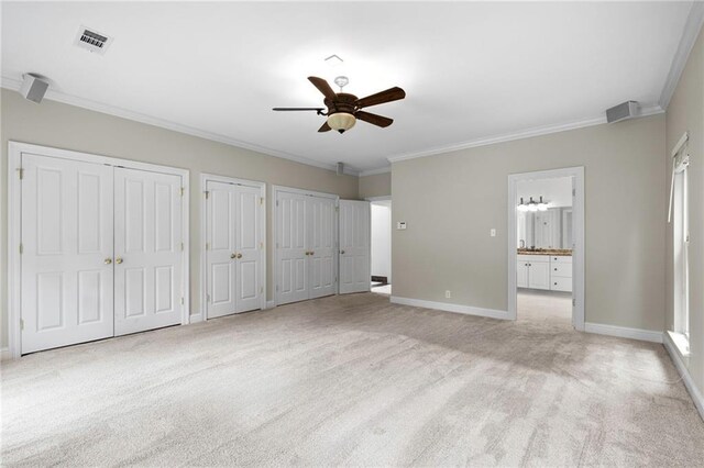 unfurnished bedroom with light carpet, crown molding, ceiling fan, and ensuite bath