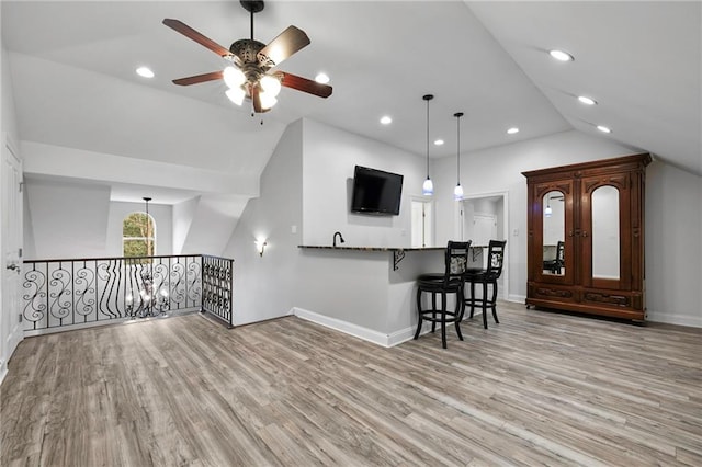 kitchen with a kitchen breakfast bar, hardwood / wood-style flooring, ceiling fan, and hanging light fixtures