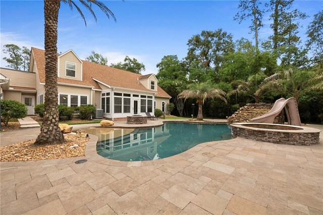 view of swimming pool with a patio area, a sunroom, central AC, and a water slide