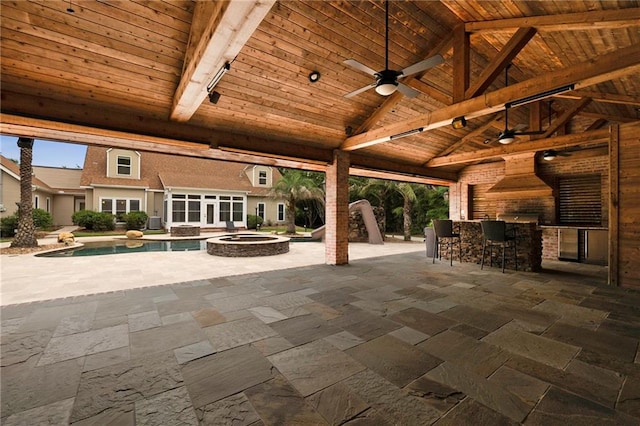 view of patio / terrace featuring an outdoor fire pit, ceiling fan, exterior kitchen, and a bar