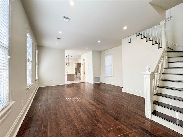 unfurnished living room with plenty of natural light and dark hardwood / wood-style flooring