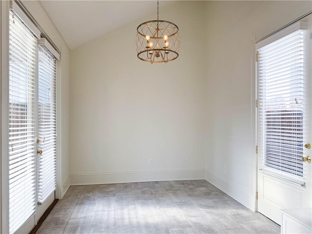 empty room featuring a healthy amount of sunlight, an inviting chandelier, and lofted ceiling