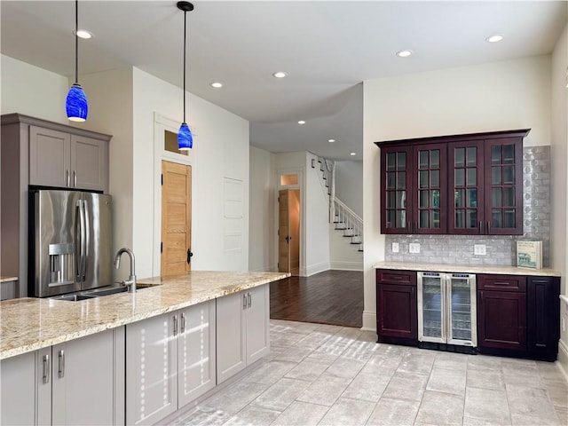 kitchen featuring backsplash, hanging light fixtures, sink, stainless steel fridge with ice dispenser, and beverage cooler