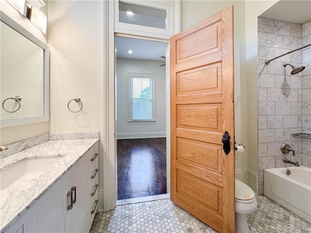 full bathroom with vanity, hardwood / wood-style flooring, toilet, and tiled shower / bath combo