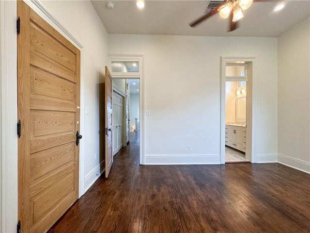 unfurnished bedroom with ceiling fan, ensuite bathroom, and dark wood-type flooring