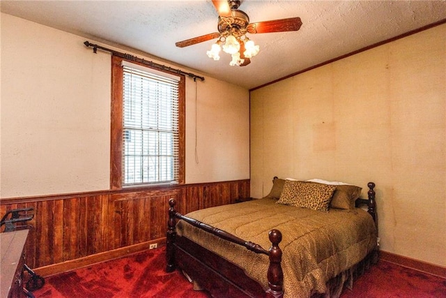 4102 Dauphine St, New Orleans, LA 70117 - bedroom with carpet, wainscoting, wood walls, a textured ceiling, and a ceiling fan