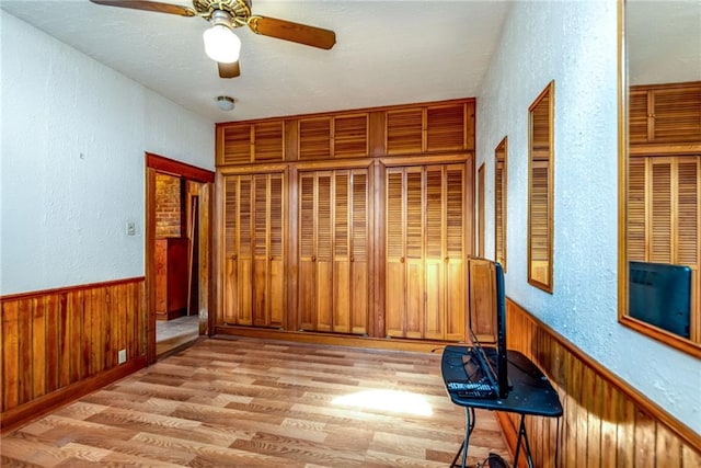4102 Dauphine St, New Orleans, LA 70117 - unfurnished bedroom with a textured wall, light wood-type flooring, wooden walls, a wainscoted wall, and ceiling fan