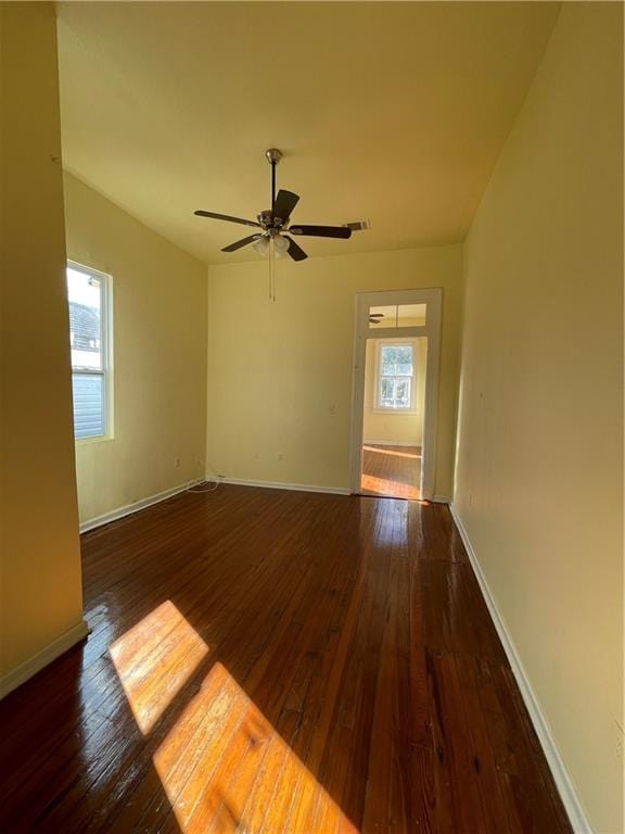 empty room with dark hardwood / wood-style floors, plenty of natural light, and ceiling fan