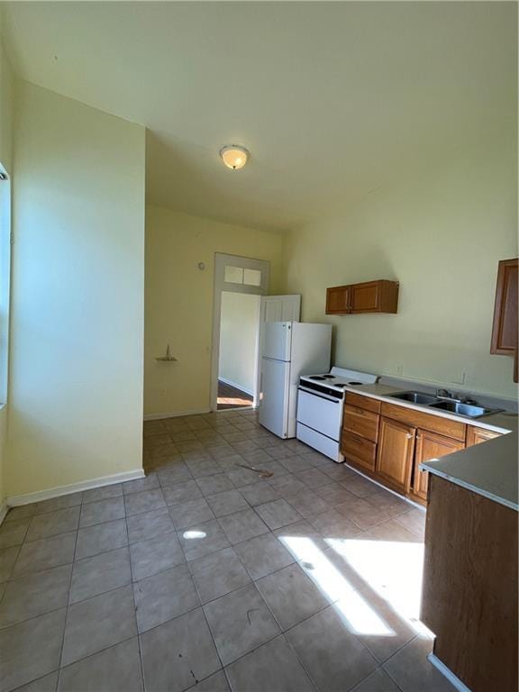 kitchen with sink, light tile patterned floors, and white appliances