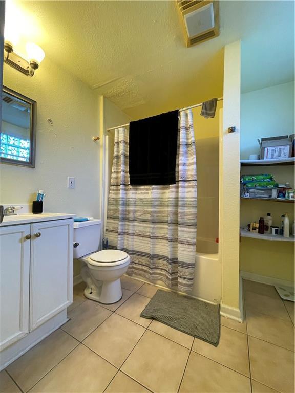 full bathroom featuring toilet, vanity, tile patterned floors, and shower / tub combo with curtain