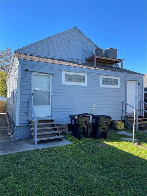 back of property featuring a lawn and central AC