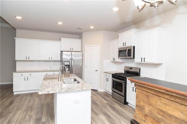 kitchen featuring backsplash, an island with sink, white cabinets, and stainless steel appliances