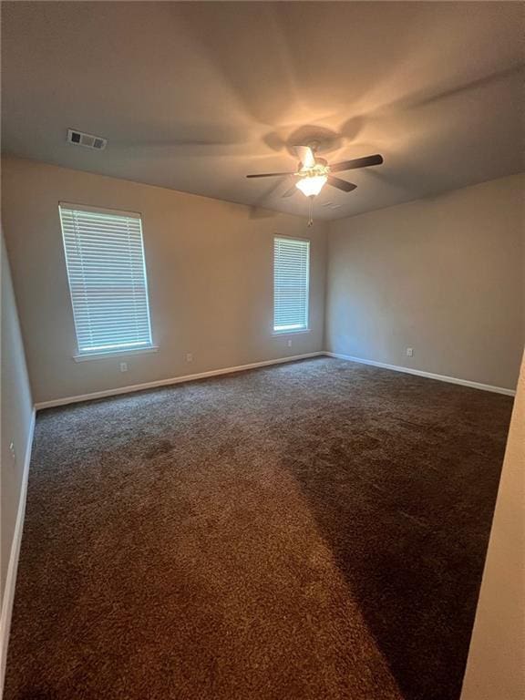 spare room with dark colored carpet and ceiling fan