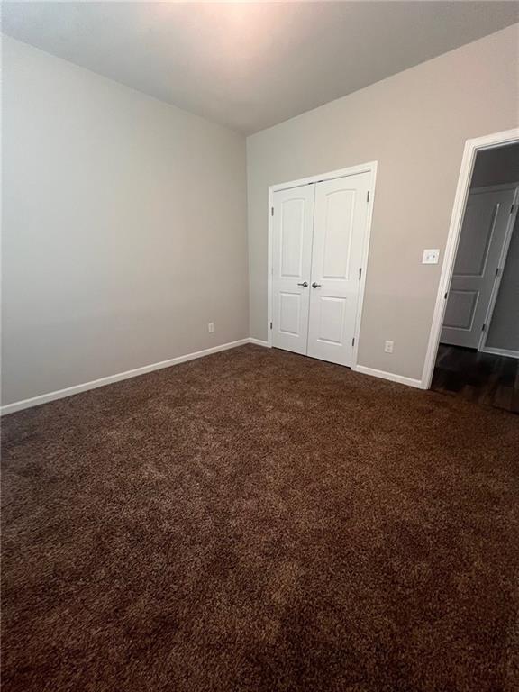 unfurnished bedroom featuring a closet and dark carpet