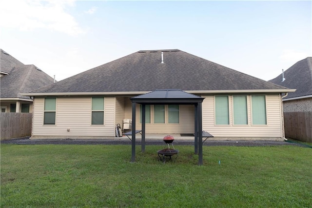 rear view of house featuring a gazebo and a lawn