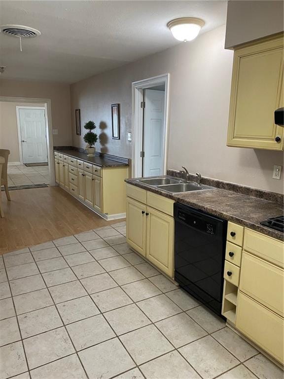 kitchen with sink, light tile patterned floors, black appliances, and cream cabinets