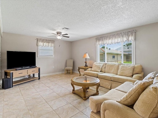 living room with ceiling fan, plenty of natural light, a textured ceiling, and light tile patterned floors