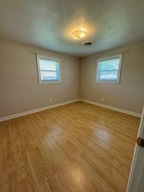 empty room featuring a textured ceiling and light wood-type flooring