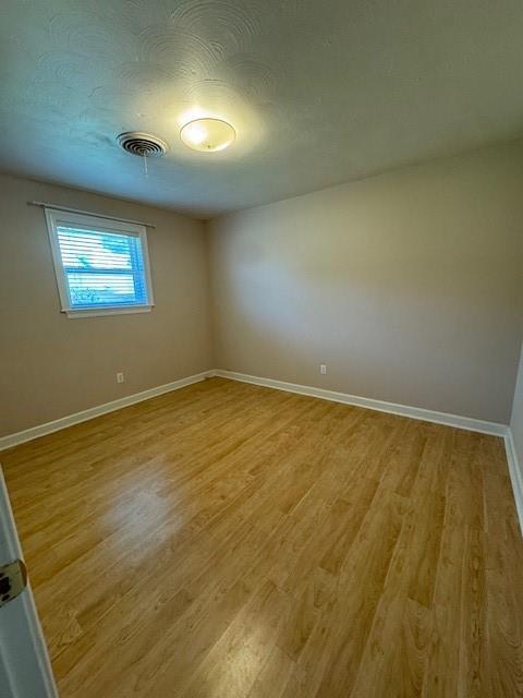 unfurnished room featuring a textured ceiling and light wood-type flooring