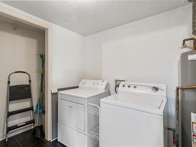 washroom with water heater, separate washer and dryer, and a textured ceiling