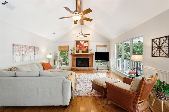 living room featuring a brick fireplace, ceiling fan, vaulted ceiling, and hardwood / wood-style flooring