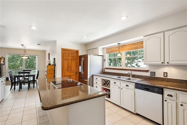 kitchen with white dishwasher, stainless steel fridge, a center island, and a wealth of natural light