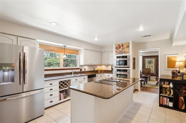 kitchen featuring a center island, sink, dark stone countertops, appliances with stainless steel finishes, and white cabinetry