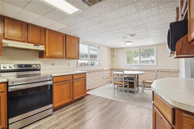 kitchen with brick wall, stainless steel range with electric stovetop, and light hardwood / wood-style flooring