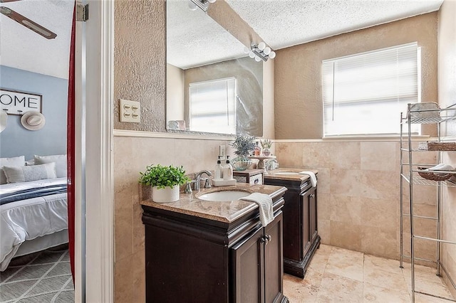 bathroom featuring a textured ceiling, vanity, and tile walls