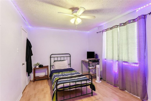 bedroom featuring a textured ceiling, light wood-type flooring, and ceiling fan