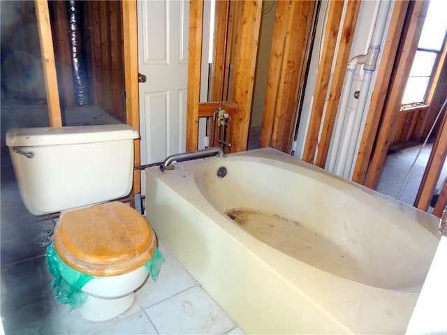 bathroom with tile patterned flooring, a tub to relax in, and toilet