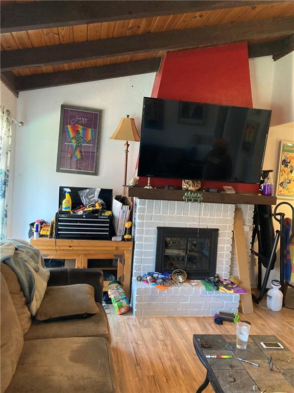 living room with hardwood / wood-style flooring, vaulted ceiling with beams, wooden ceiling, and a fireplace