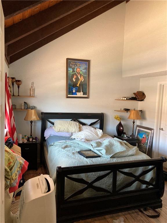 bedroom featuring lofted ceiling with beams and hardwood / wood-style floors