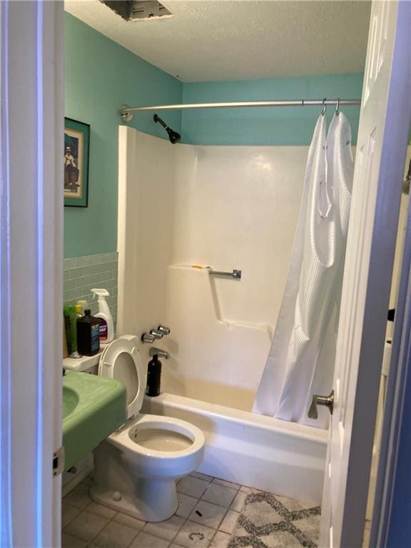 bathroom featuring toilet, shower / bath combo, a textured ceiling, and tile patterned floors