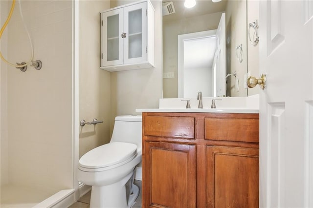 bathroom with a tile shower, oversized vanity, and toilet