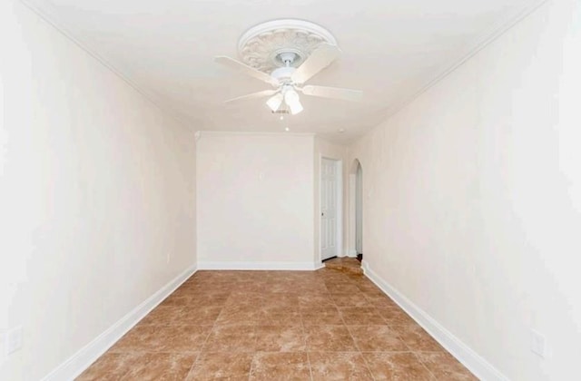 spare room with baseboards, arched walkways, ceiling fan, and crown molding