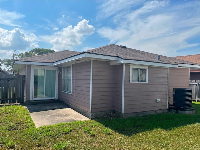 rear view of property with central AC and a yard